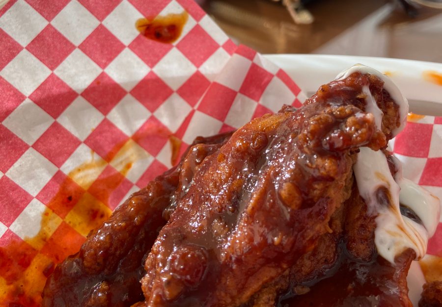 Alitas BBQ servidas en canastilla de papel a cuadros.