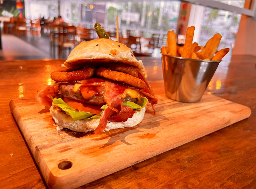 Hamburguesa doble con tocino servida sobre tabla de madera.